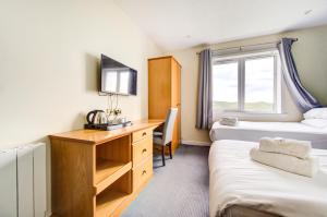 a bedroom with two beds and a desk and a window at The Morar Hotel in Morar