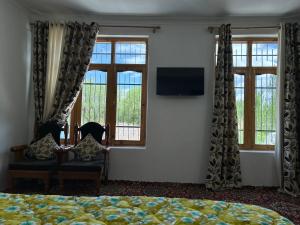 a bedroom with a bed and two chairs and windows at Nature Palace Farmstay in Shey