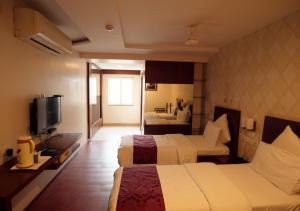 a hotel room with two beds and a television at Hotel Sasya Pride in Kurnool