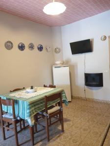 comedor con mesa, sillas y TV en Casa Di Collina Nelle Langhe Typical country house, en Belvedere Langhe