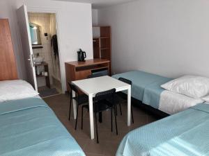 ジビジノにあるPokoje Na Złotych Wydmachのベッド2台、白いテーブルと椅子が備わる客室です。