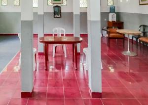 - une table et des chaises dans une pièce dotée d'un sol rouge dans l'établissement Villa Anyelir Yustik Mitra RedDoorz, 