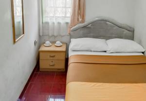 - une petite chambre avec 2 lits et une table de nuit dans l'établissement Villa Anyelir Yustik Mitra RedDoorz, 