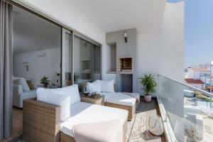 a living room with white furniture on a balcony at Burgau Village and Sea in Burgau
