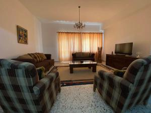 a living room with two couches and a television at Lovely 3 Bedrooms Apartment at city center in Bayt Jālā