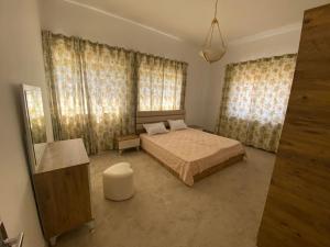 a bedroom with a bed and two windows with curtains at Lovely 3 Bedrooms Apartment at city center in Bayt Jālā