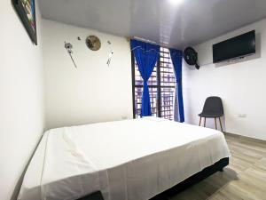 a bedroom with a white bed and a window at Apartaestudio para estrenar La Quinta in Ibagué