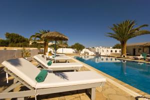a swimming pool with chaise lounge chairs next to a resort at Alafouzos Studios & Apartments in Kamari