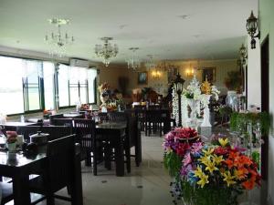 uma sala de jantar com mesas, cadeiras e flores em Doi Samoe Dao Hostel em Nan