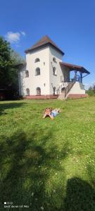 a woman laying on the grass in front of a building at Owczarkowa Zagroda 