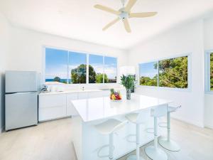 a white kitchen with a ceiling fan and white appliances at Villa Maviela Sea View 2 Bdr in Koh Samui