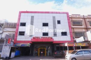 een rood-wit gebouw met een bord erop bij Hotel Permata Makassar Mitra RedDoorz in Balangberu