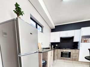 a kitchen with white cabinets and a refrigerator at Luxury Lowveld Apartment in Nelspruit