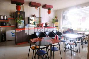 a restaurant with tables and chairs and a counter at Hotel Permata Makassar Mitra RedDoorz in Balangberu