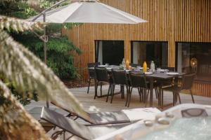 a wooden deck with a table with chairs and an umbrella at Grand loft avec Jacuzzi et Home Cinema in Saint-Brieuc