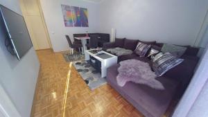 a living room with a purple couch and a table at Cezar Apartment in Belgrade