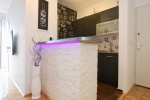 a kitchen with a brick counter with purple lighting at Cezar Apartment in Belgrade