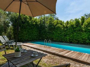 UzzanoにあるIdyllic Holiday Home in Pescia with Swimming Poolのスイミングプールの横にある木製テーブル(傘付)
