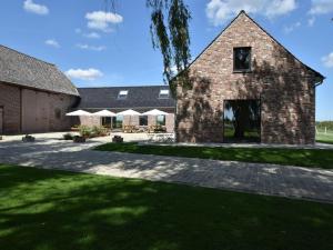 een groot bakstenen huis met een grasveld bij Spacious Holiday Home with Pond in Poperinge in Roesbrugge-Haringe