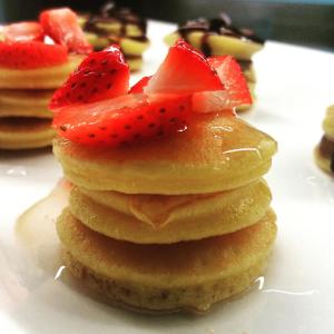 une pile de crêpes avec des fraises sur le dessus dans l'établissement Hotel HamilTown, à Cattolica