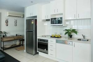 a kitchen with a stainless steel refrigerator and white cabinets at ZANZIBAR FANTASTIC 1 Bedroom APARTMENT in Gold Coast