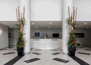 a lobby with two potted plants and a woman standing at a counter at ZANZIBAR FANTASTIC 1 Bedroom APARTMENT in Gold Coast