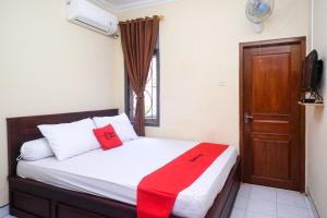 - une chambre avec un lit et une couverture rouge dans l'établissement RedDoorz near Candi Ratu Boko 2, à Tanjungtirto
