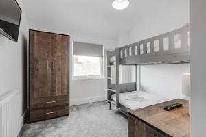 a bedroom with a bunk bed and a wooden cabinet at St David's - Stylish 2 bed apartment, free parking, close to beach in Lytham St Annes