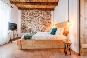 a bedroom with a wooden bed and a stone wall at Casa Nostra - Garda Rooms in Cavalcaselle