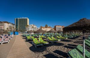 a bunch of chairs and umbrellas on a beach at Leonardo Hotel Fuengirola Costa del Sol in Fuengirola