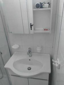 uma casa de banho branca com um lavatório e um espelho em Serene appartment at St. Ioannis em Agios Ioannis Pelion
