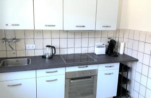 uma cozinha com armários brancos e um lavatório em Theox Apartment No 8 - 90qm mit 2 Schlafzimmern und 5 Betten em Duisburgo