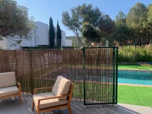 eine Terrasse mit 2 Stühlen und einem Zaun mit Pool in der Unterkunft La Fosca Dream in Palamós