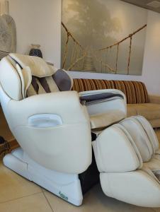a white reclining chair and a couch in a room at Roy Vacation Home in Rishon LeẔiyyon