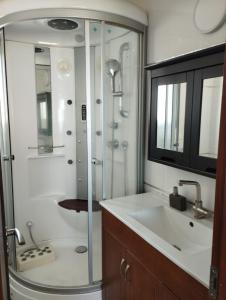 a bathroom with a glass shower and a sink at Roy Vacation Home in Rishon LeẔiyyon