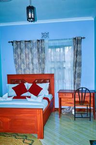 a bedroom with a bed and a desk and a window at Safari Park House in Arusha