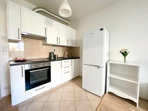 a kitchen with white cabinets and a refrigerator at Centrum Park Studio in Prague