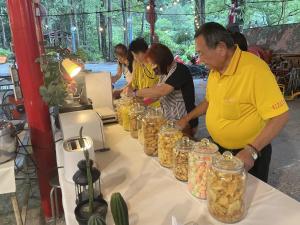 a group of people standing around a table with jars of food at De Wang Villa in Meinong