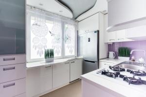 a white kitchen with a sink and a refrigerator at Apartament Lelewela in Częstochowa