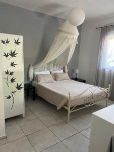 1 dormitorio con 1 cama blanca con dosel en Alexandros Apartments, en Dhrepanon