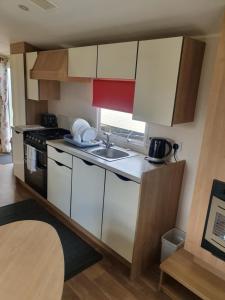 eine kleine Küche mit weißen Schränken und einem Waschbecken in der Unterkunft Fantasy Island King Fisher 8Berth 402 in Ingoldmells