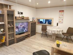 a living room with a large television and a table at Ferienwohnung Helm in Wilnsdorf