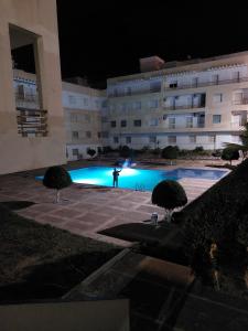 a swimming pool in front of a building at night at Residence les jardins cap de l eau in Ras El Ma