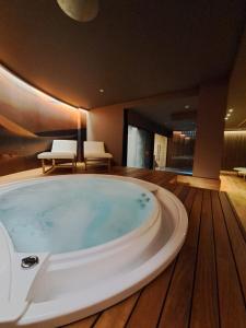 Biancodonda Lifestyle Hotel & SPA في غالّيبولي: حوض استحمام كبير في غرفة مع أرضية خشبية