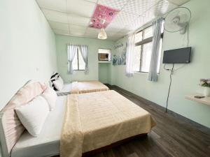 a room with two beds and a tv in it at De Wang Villa in Meinong