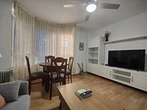 Una sala de estar con un televisor y una mesa y sillas. en Apartamento El Rinconcito de Martina, en Jarandilla de la Vera