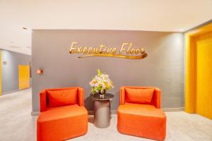 two orange chairs in a waiting room with a sign at Ibos Hotels Izmir Alsancak in Alsancak