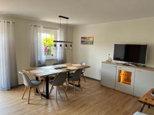 a dining room with a table and chairs and a television at Naturstrand Apartment - 86m² - 4 Betten - Parkplatz in Hagermarsch