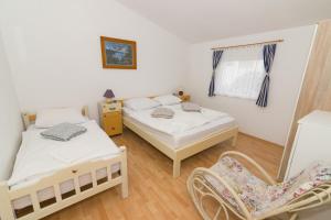 een slaapkamer met 2 bedden en een stoel bij Apartments Besa in Pirovac