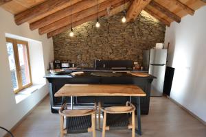 uma cozinha com uma ilha negra e uma mesa de madeira em Skyfall Maison em Valcebollère